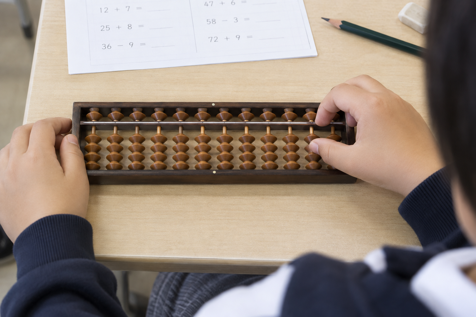 そろばんの珠を動かして計算を練習する小学生の手元のイメージ