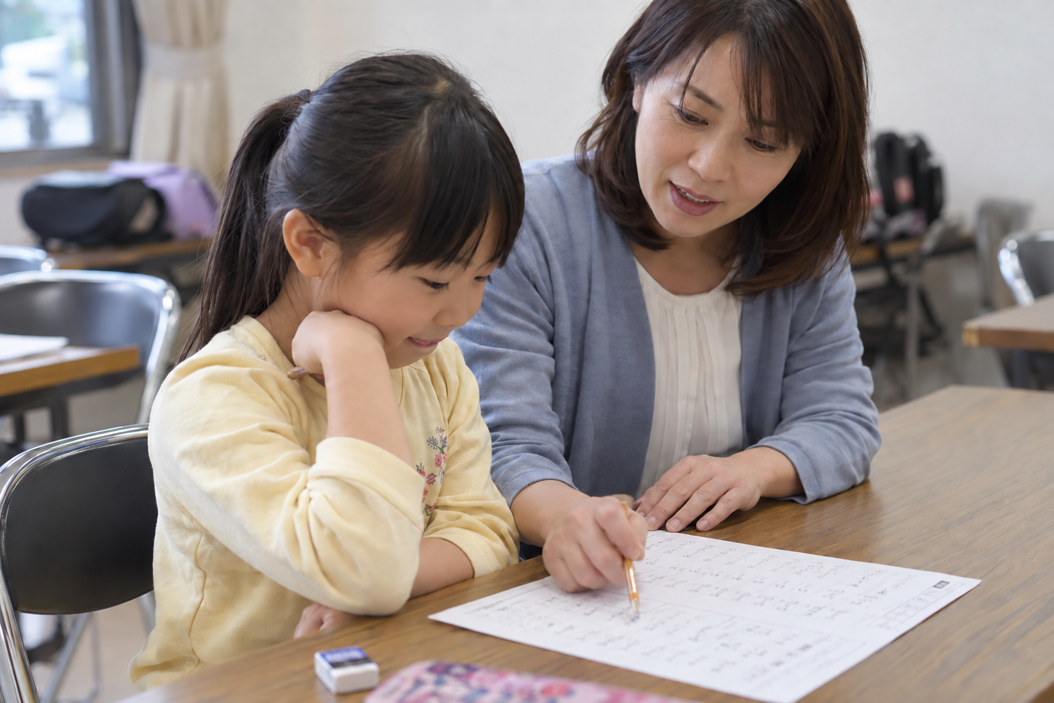 先生と一緒に答案を見直す小学生のイメージ